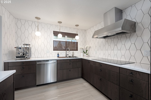 kitchen with stainless steel dishwasher, black electric cooktop, sink, wall chimney range hood, and hanging light fixtures