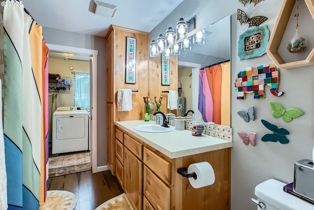 bathroom featuring visible vents, toilet, wood finished floors, washer / dryer, and vanity