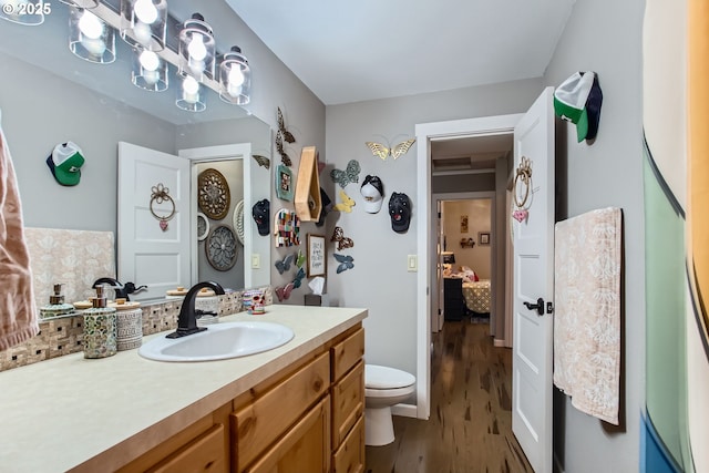 ensuite bathroom featuring vanity, ensuite bath, toilet, and wood finished floors