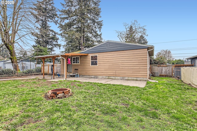 back of house with a yard, a fire pit, and a fenced backyard