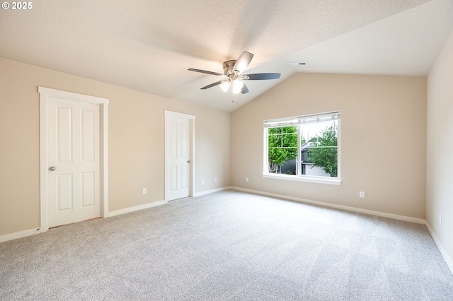 unfurnished bedroom featuring carpet floors, baseboards, vaulted ceiling, and a ceiling fan