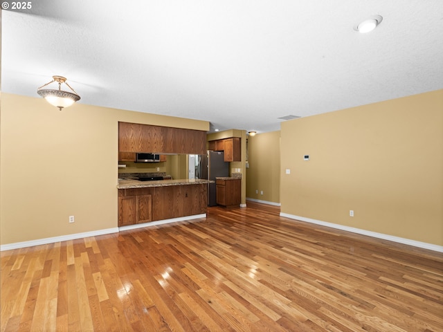 14300 Sherbrook Pl, Lake Oswego, OR 97035 - kitchen featuring open floor plan, appliances with stainless steel finishes, brown cabinetry, a peninsula, and light wood finished floors