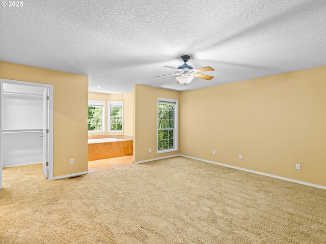 14300 Sherbrook Pl, Lake Oswego, OR 97035 - unfurnished bedroom with carpet flooring, a walk in closet, baseboards, a textured ceiling, and a ceiling fan