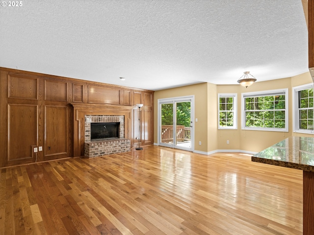 14300 Sherbrook Pl, Lake Oswego, OR 97035 - unfurnished living room with light wood-style floors, a textured ceiling, a brick fireplace, and baseboards