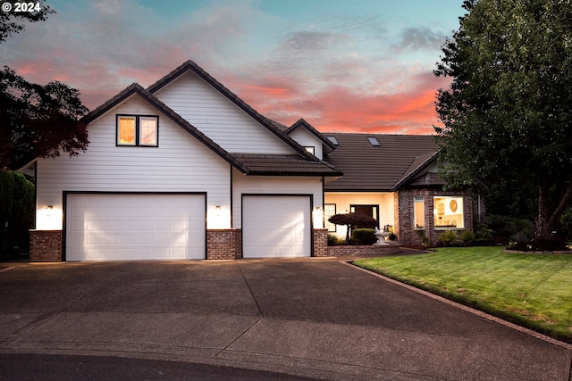 view of front of property with concrete driveway, brick siding, and a lawn