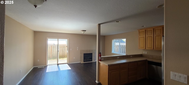 kitchen with tile countertops, a textured ceiling, stainless steel dishwasher, dark hardwood / wood-style floors, and a tiled fireplace