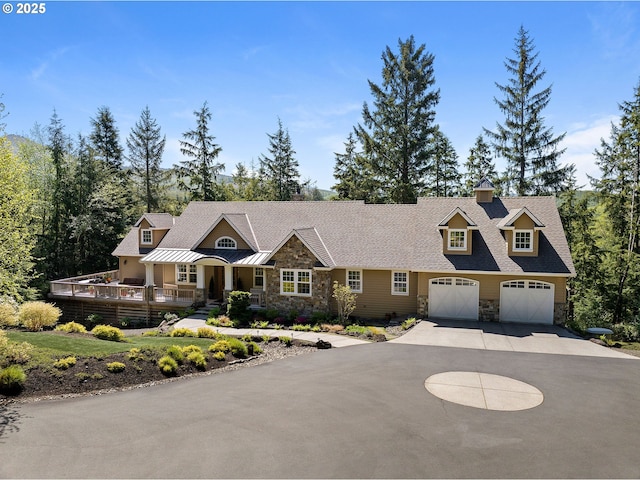 33525 Beerman Creek Ln, Seaside, OR 97138 - view of front facade featuring stone siding, a garage, driveway, a deck, and a standing seam roof