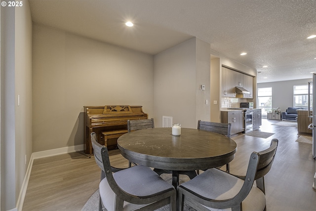 dining space with light wood-style floors, a textured ceiling, recessed lighting, baseboards, and visible vents