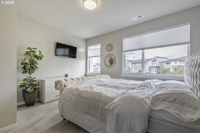 bedroom featuring visible vents, baseboards, and light carpet