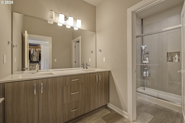 full bathroom with a sink, a shower stall, and wood finished floors