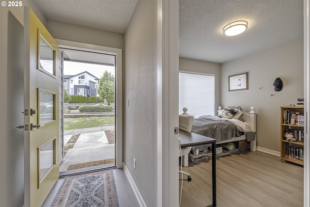 interior space featuring a healthy amount of sunlight, baseboards, light wood finished floors, and a textured ceiling
