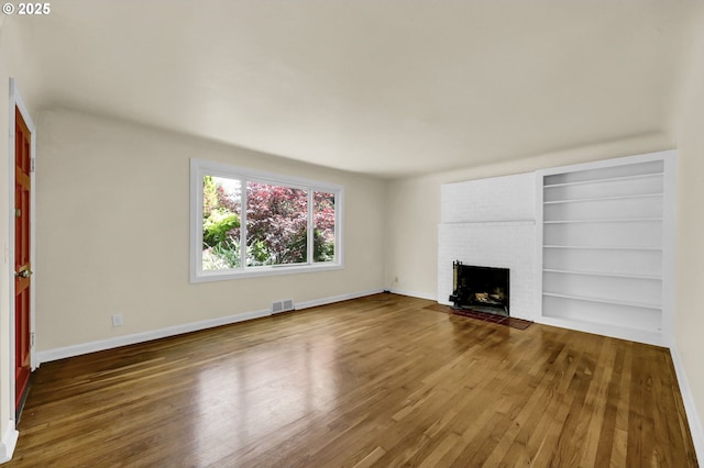 2674 Kincaid St, Eugene, OR 97405 - unfurnished living room with wood finished floors, a brick fireplace, baseboards, and built in shelves