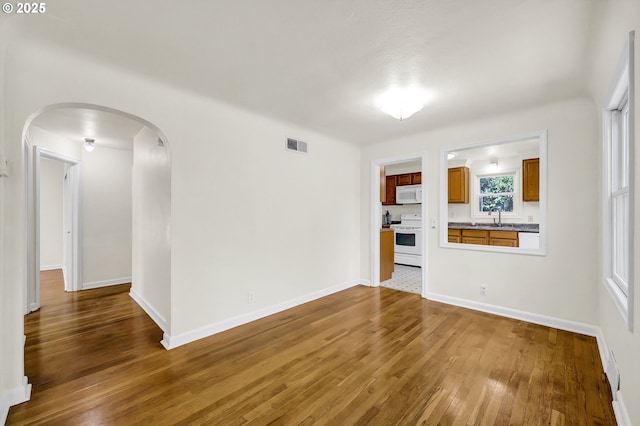 2674 Kincaid St, Eugene, OR 97405 - unfurnished living room with a sink, wood-type flooring, arched walkways, and baseboards