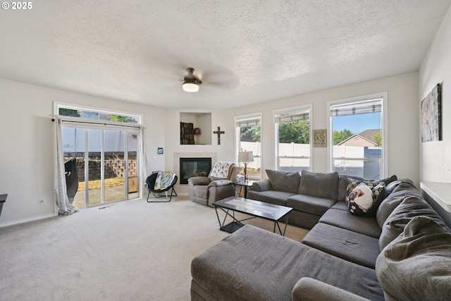 302 NW Elderberry Ln, Dallas, OR 97338 - carpeted living room with a textured ceiling, a ceiling fan, healthy amount of natural light, and a glass covered fireplace