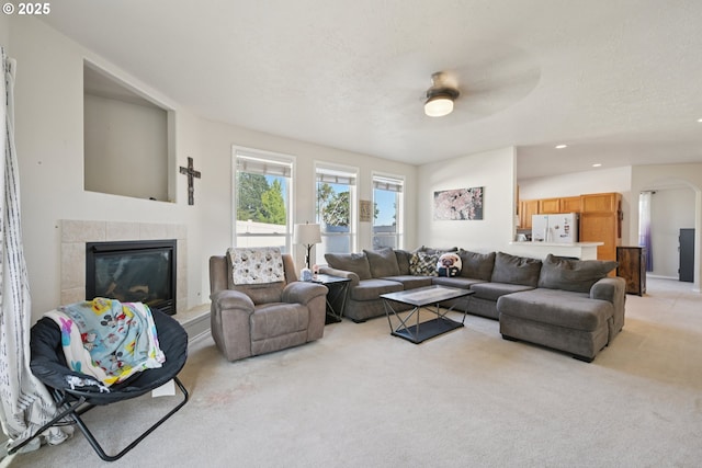 302 NW Elderberry Ln, Dallas, OR 97338 - living area featuring light colored carpet, a tiled fireplace, arched walkways, a ceiling fan, and recessed lighting