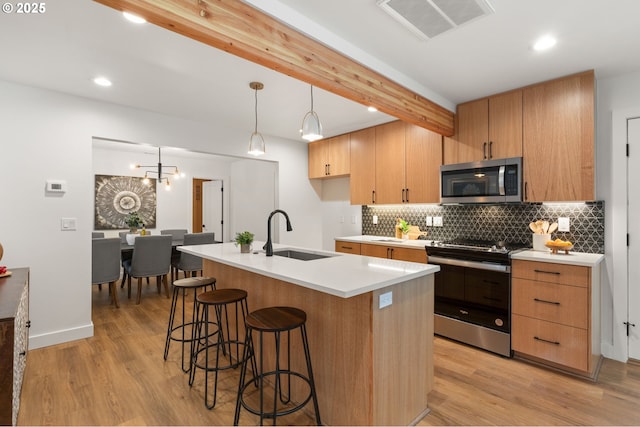 kitchen with beam ceiling, visible vents, backsplash, appliances with stainless steel finishes, and a sink