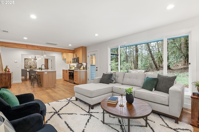 living area with baseboards, light wood finished floors, visible vents, and recessed lighting