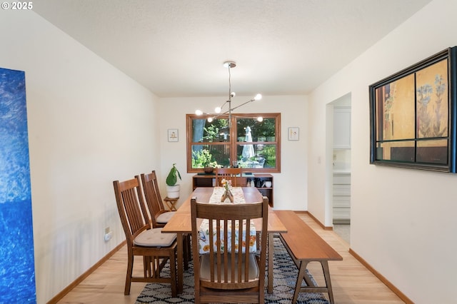 dining area featuring a chandelier, light wood-style flooring, and baseboards