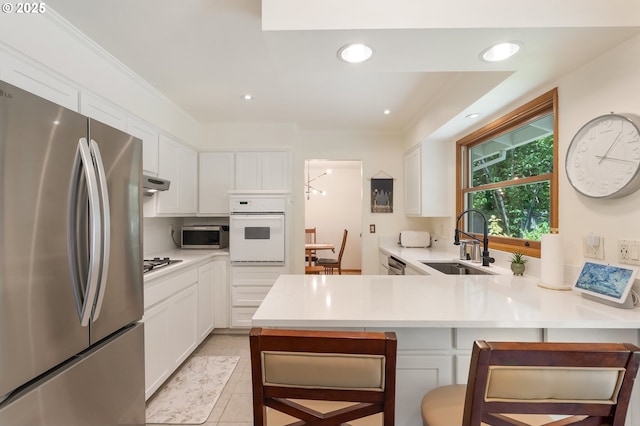 kitchen with stainless steel appliances, a sink, a peninsula, white cabinets, and recessed lighting