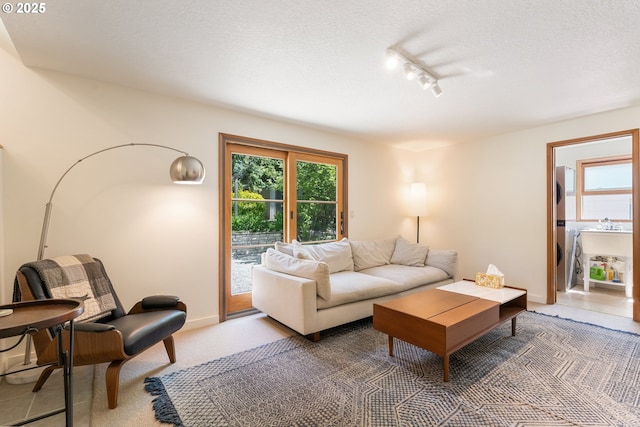 living area with a textured ceiling, track lighting, and baseboards