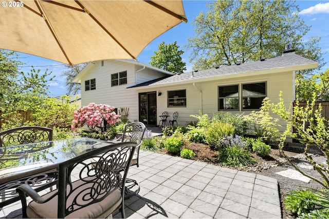 back of house with a patio, outdoor dining area, fence, and roof with shingles