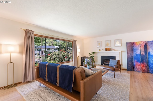 living area with wood finished floors, a brick fireplace, and a textured ceiling