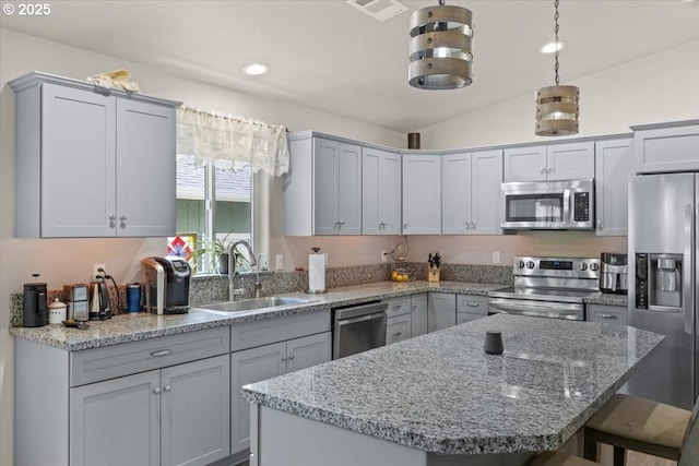 kitchen featuring stainless steel appliances, a sink, a kitchen breakfast bar, light stone counters, and vaulted ceiling