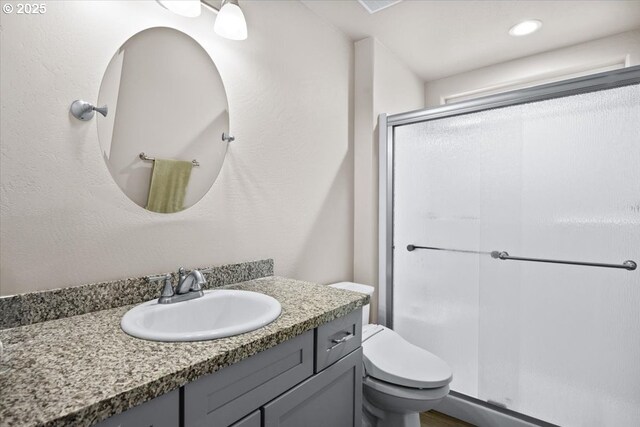 bathroom with toilet, a stall shower, and vanity