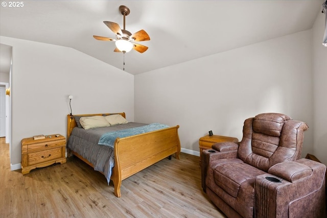 bedroom featuring light wood finished floors, baseboards, lofted ceiling, and a ceiling fan