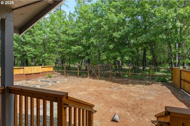 fenced backyard featuring a garden and view of wooded area