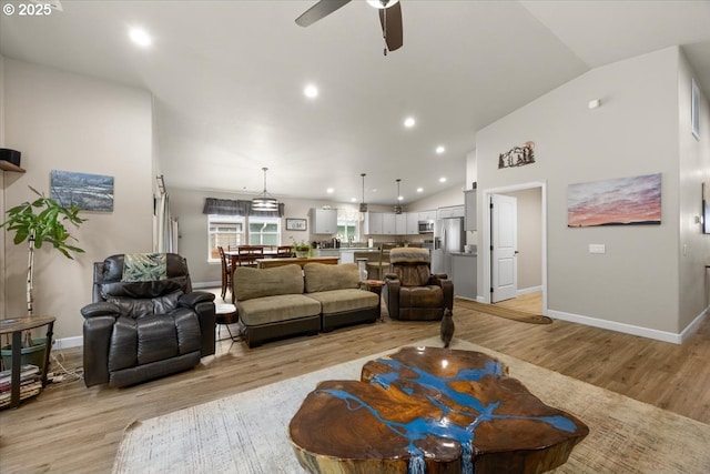 living area with vaulted ceiling, light wood finished floors, ceiling fan, baseboards, and recessed lighting
