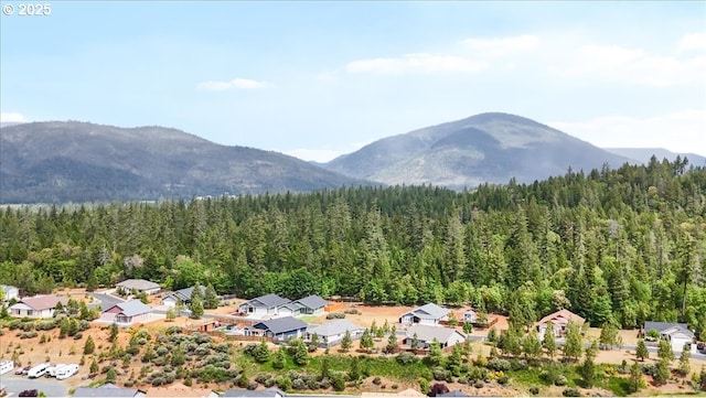 view of mountain backdrop featuring a heavily wooded area and nearby suburban area
