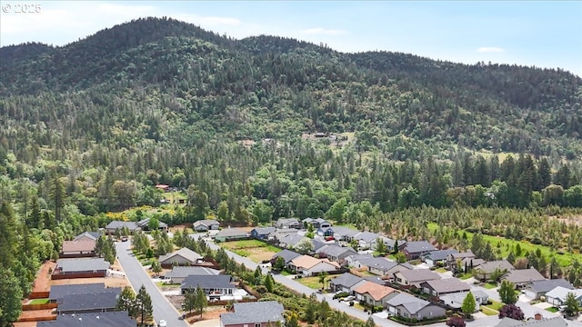 aerial view of property and surrounding area with a forest, mountains, and nearby suburban area