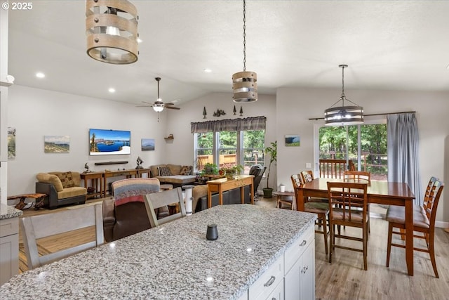 kitchen featuring lofted ceiling, light wood-style floors, a ceiling fan, open floor plan, and white cabinetry
