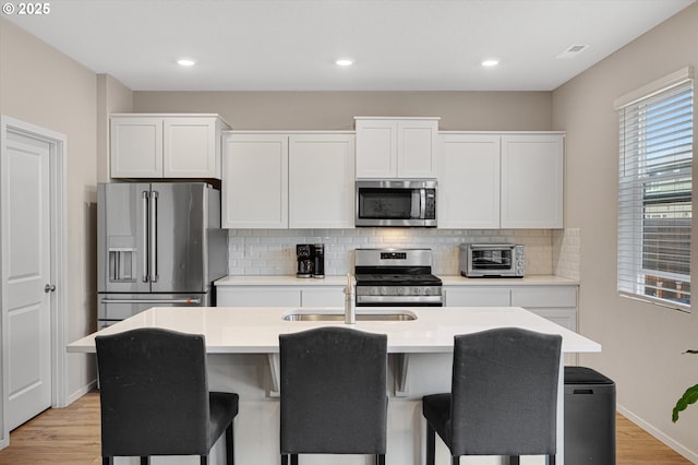 4829 Surveyor Ave, Salem, OR 97305 - kitchen with stainless steel appliances, a sink, backsplash, light wood-style flooring, and white cabinetry