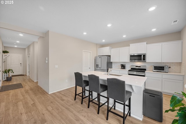 4829 Surveyor Ave, Salem, OR 97305 - kitchen featuring appliances with stainless steel finishes, decorative backsplash, a breakfast bar area, a kitchen island with sink, and recessed lighting