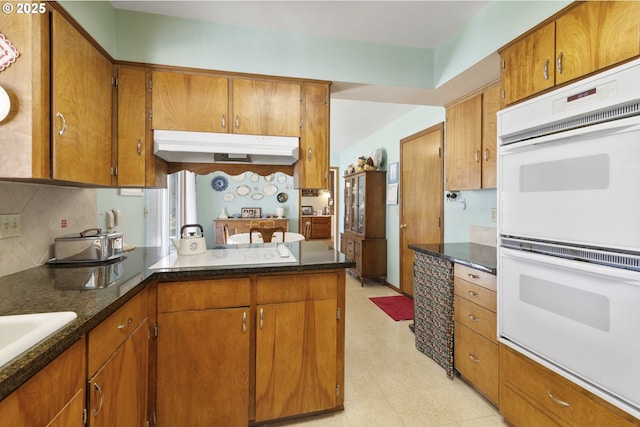 kitchen featuring sink, decorative backsplash, white double oven, and kitchen peninsula