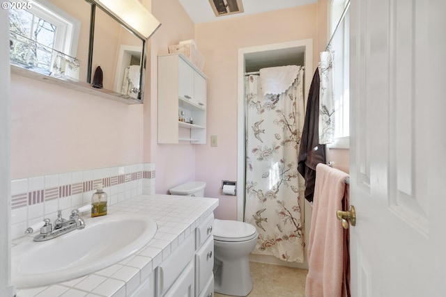 bathroom featuring vanity, backsplash, and toilet