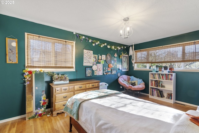 bedroom with an inviting chandelier and light hardwood / wood-style floors