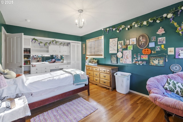 bedroom with hardwood / wood-style floors, an inviting chandelier, and a closet