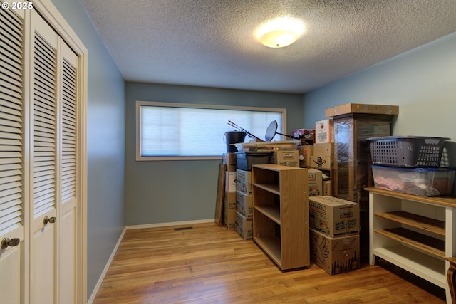 bedroom with light hardwood / wood-style floors, a closet, and a textured ceiling