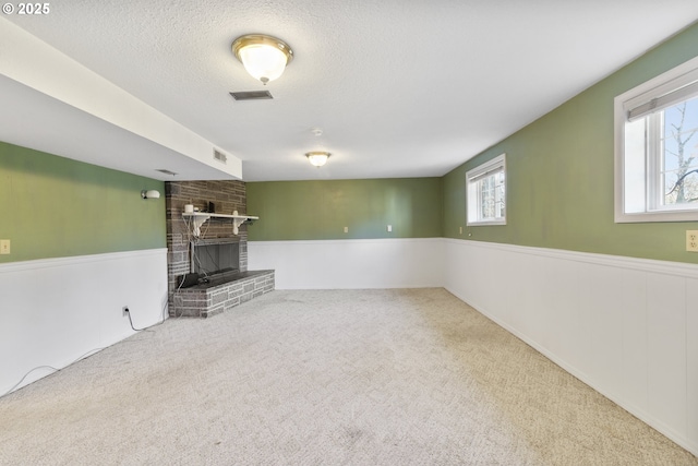 basement featuring carpet flooring, a brick fireplace, and a textured ceiling