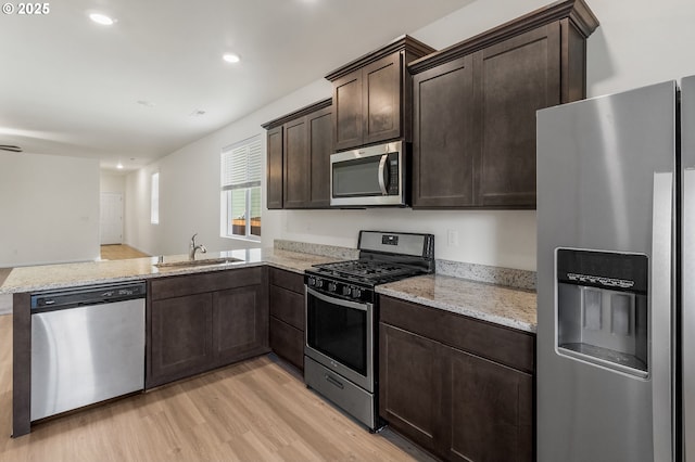 1712 W 12th St, La Center, WA 98629 - kitchen with stainless steel appliances, a sink, light wood-type flooring, dark brown cabinets, and light stone countertops