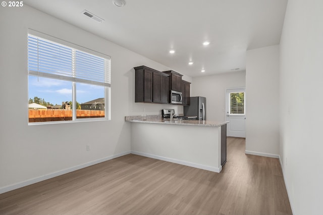 1712 W 12th St, La Center, WA 98629 - kitchen with stainless steel appliances, light wood finished floors, dark brown cabinets, baseboards, and recessed lighting