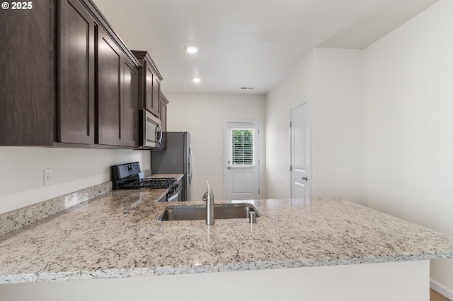 1712 W 12th St, La Center, WA 98629 - kitchen featuring stainless steel appliances, a sink, dark brown cabinetry, light stone countertops, and recessed lighting