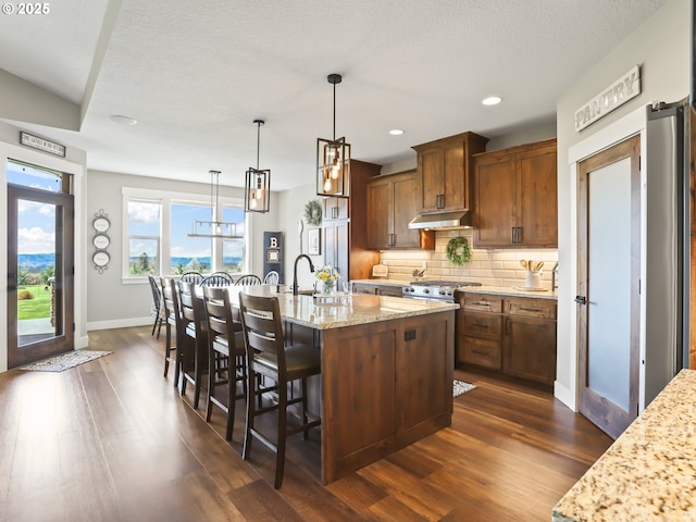 29349 SE Sunview Ln, Estacada, OR 97023 - kitchen featuring dark wood-type flooring, decorative backsplash, a kitchen island with sink, a kitchen bar, and recessed lighting