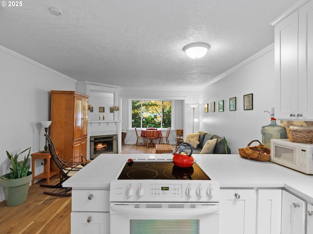 kitchen with kitchen peninsula, white cabinetry, ornamental molding, and range