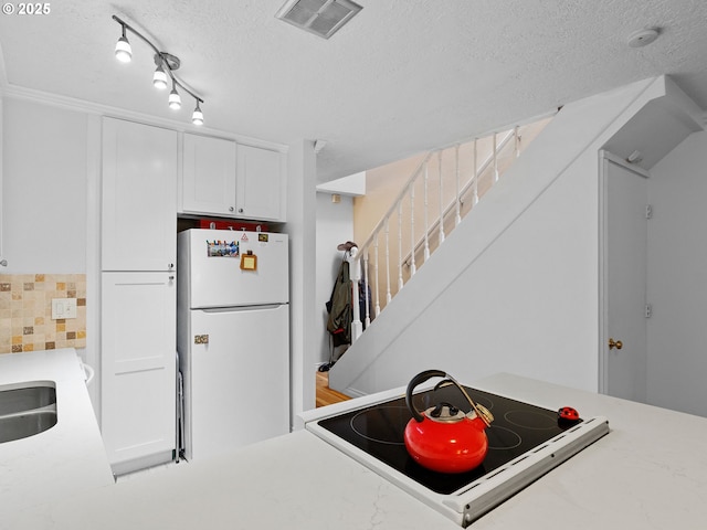 kitchen with range, white cabinetry, a textured ceiling, and white refrigerator