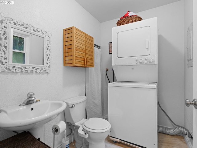 bathroom featuring hardwood / wood-style floors, toilet, stacked washer / dryer, and sink