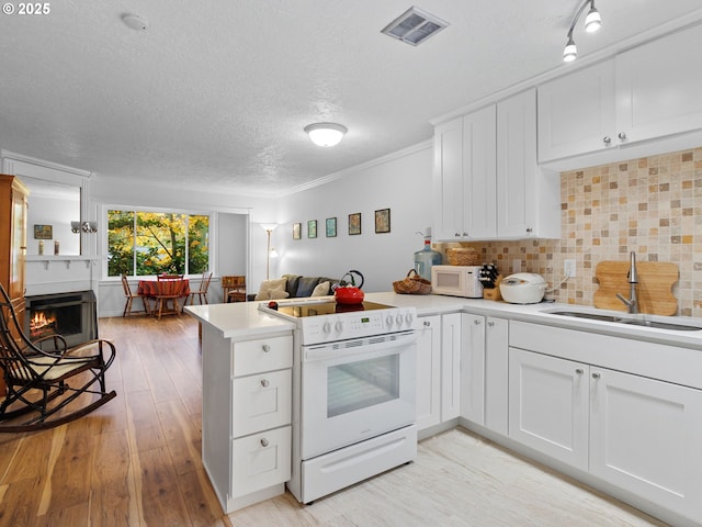 kitchen with kitchen peninsula, white appliances, white cabinetry, and sink